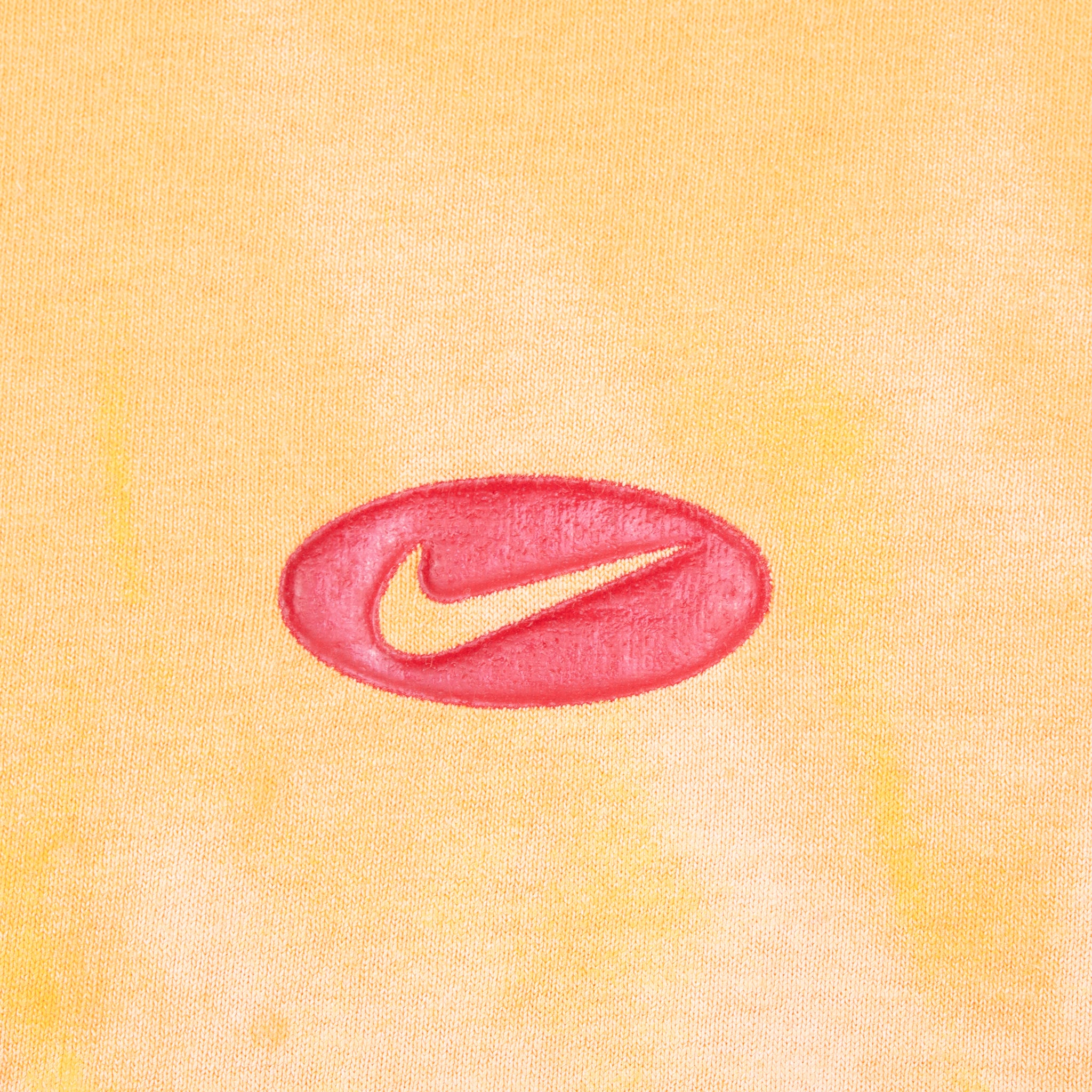Close-up of red oval Nike Swoosh embroidery on orange fabric