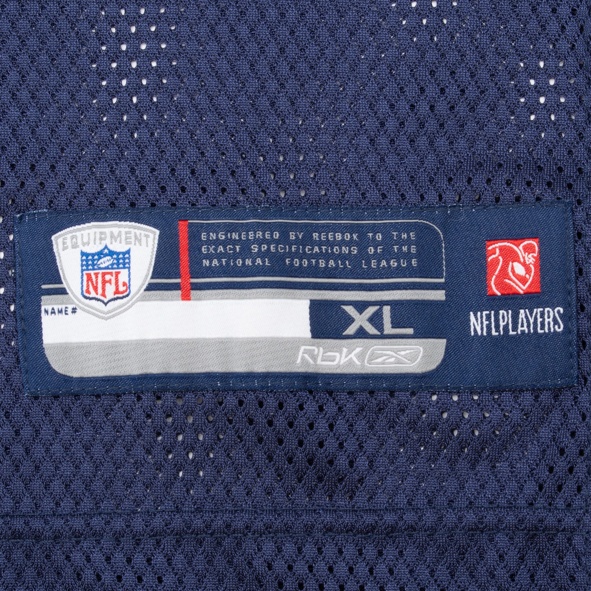 Close-up of Reebok NFL Equipment XL hem label on navy mesh jersey