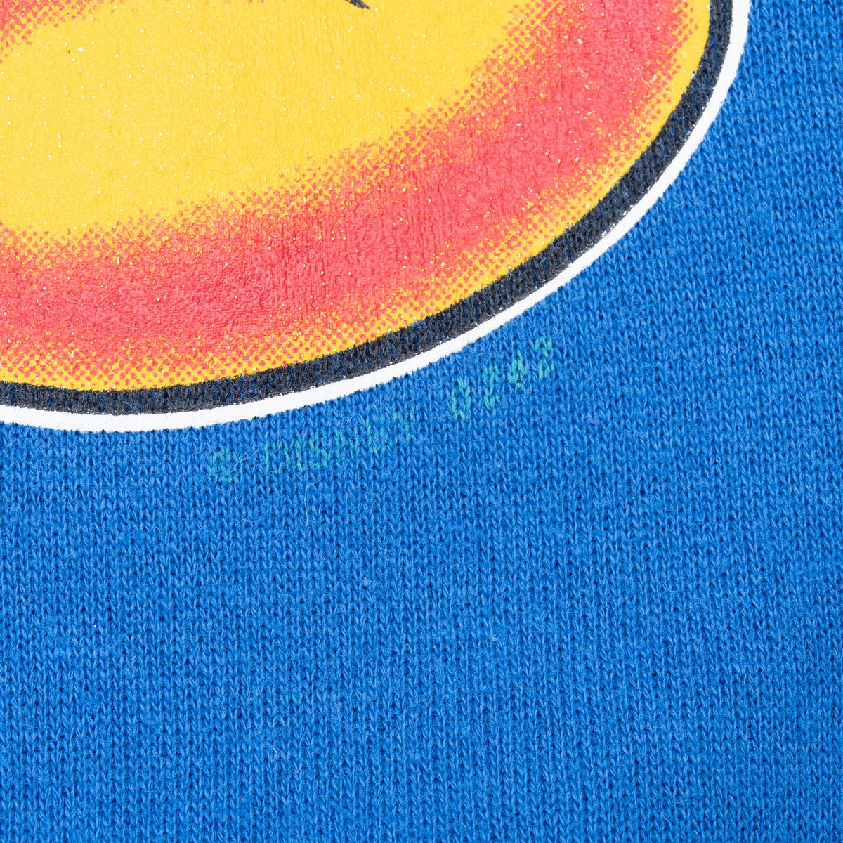 Close-up of blue sweatshirt fabric showing a small green mark beside the printed graphic