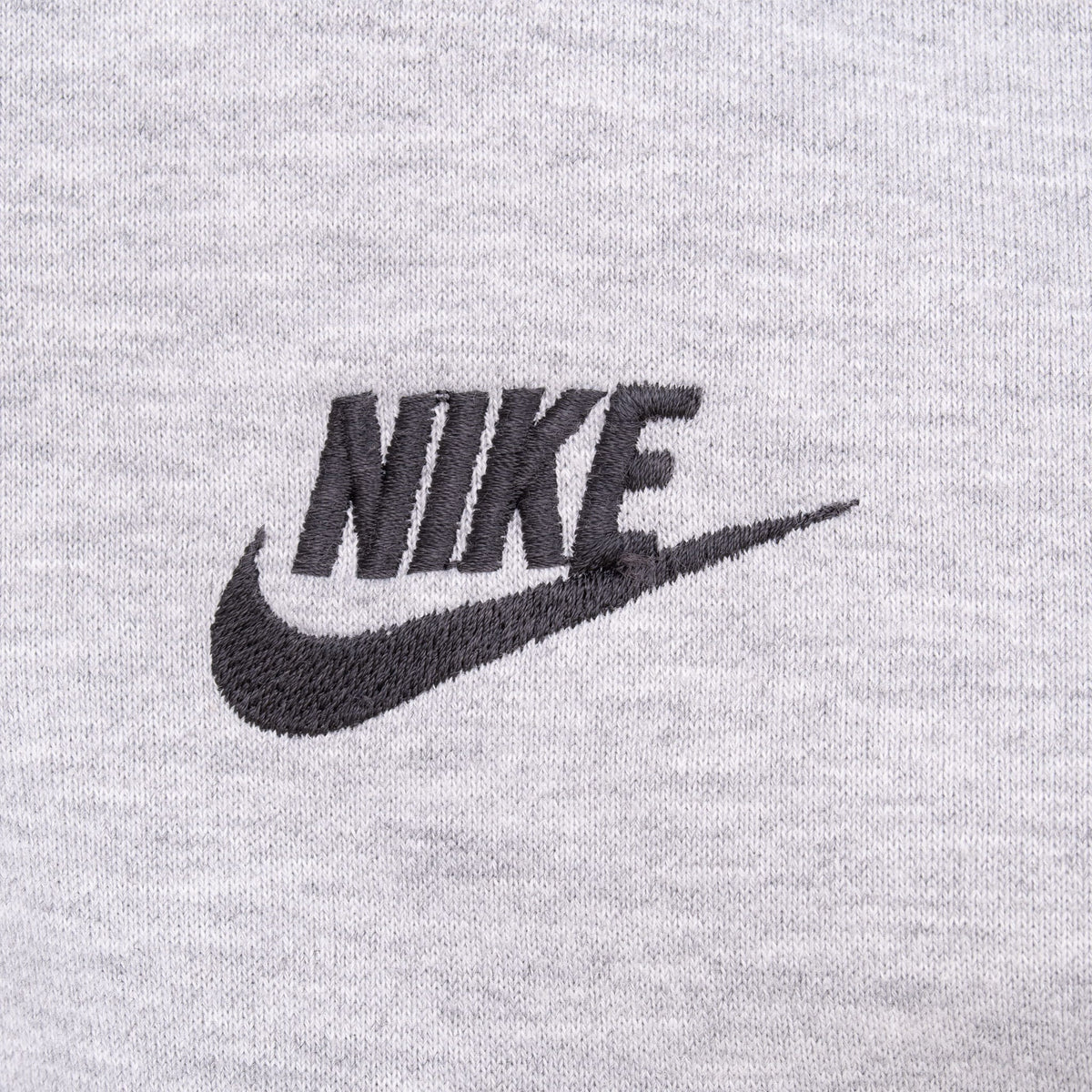 Close-up of black Nike logo embroidery on grey hoodie chest