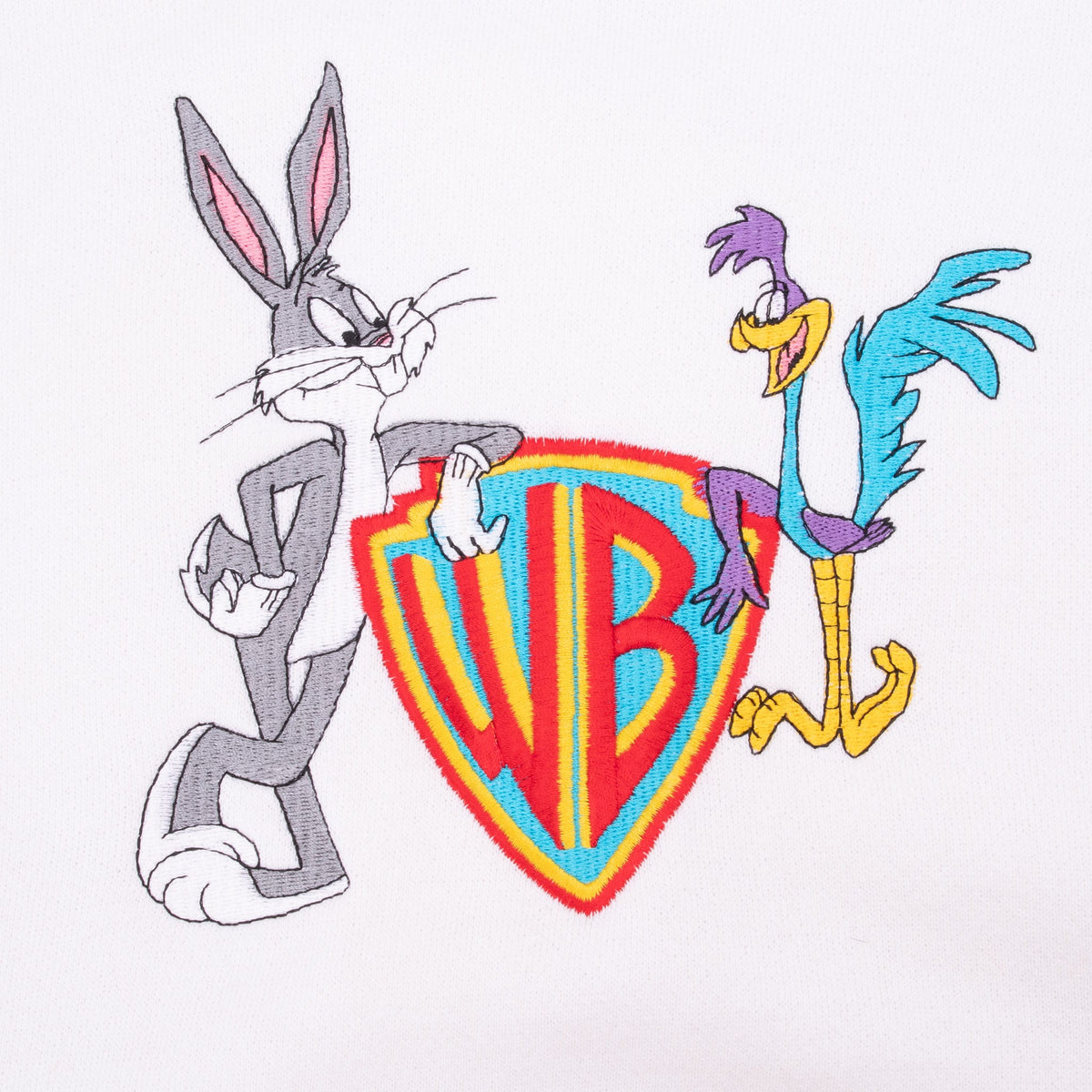 Close-up of Bugs Bunny and Road Runner beside a colorful Warner Bros. shield graphic