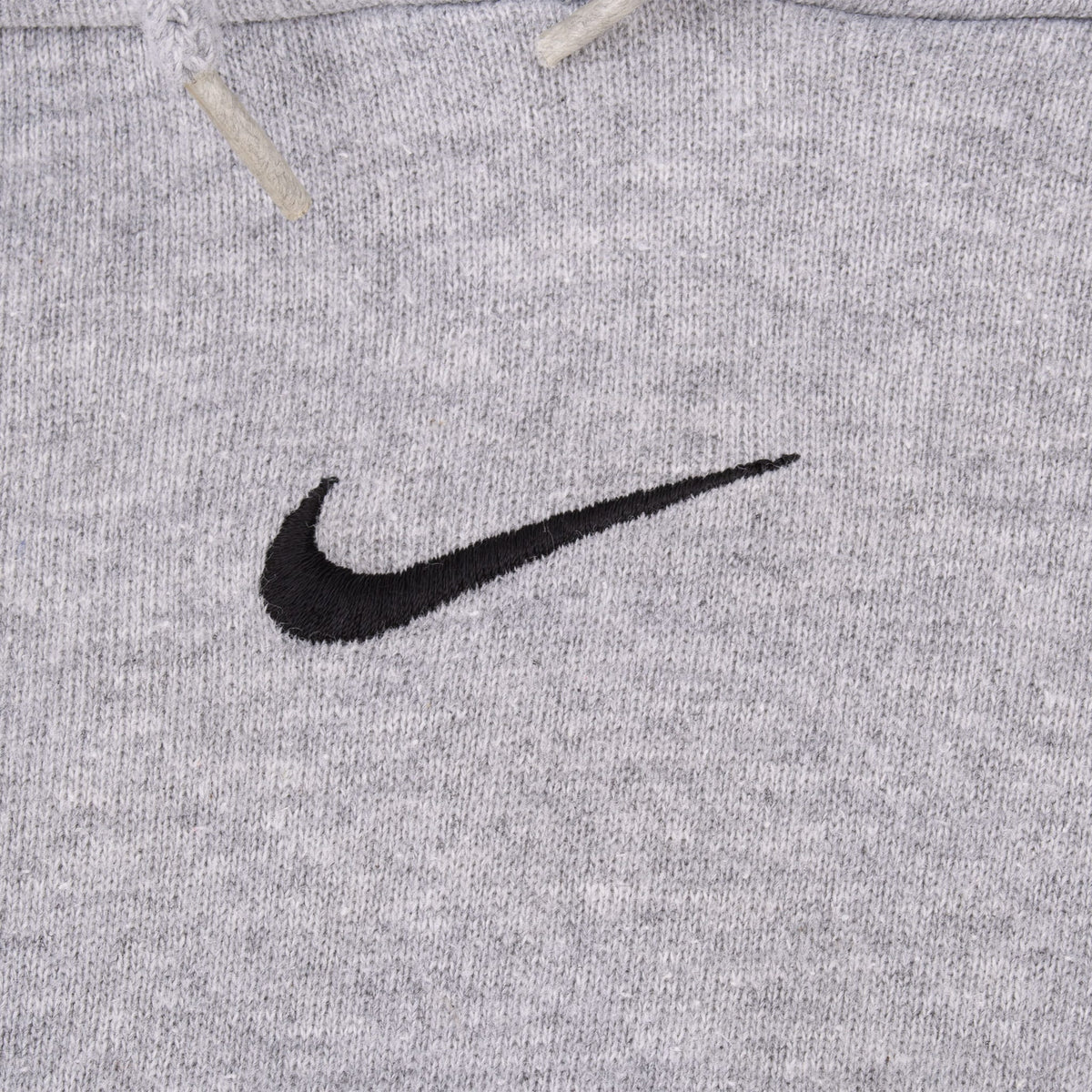 Close-up of black embroidered Nike Swoosh centered on grey hoodie chest