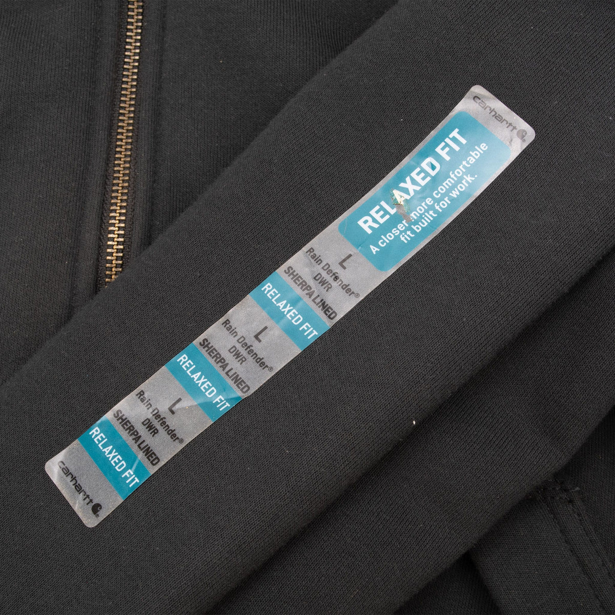 Carhartt Relaxed Fit retail sticker attached to black hoodie sleeve