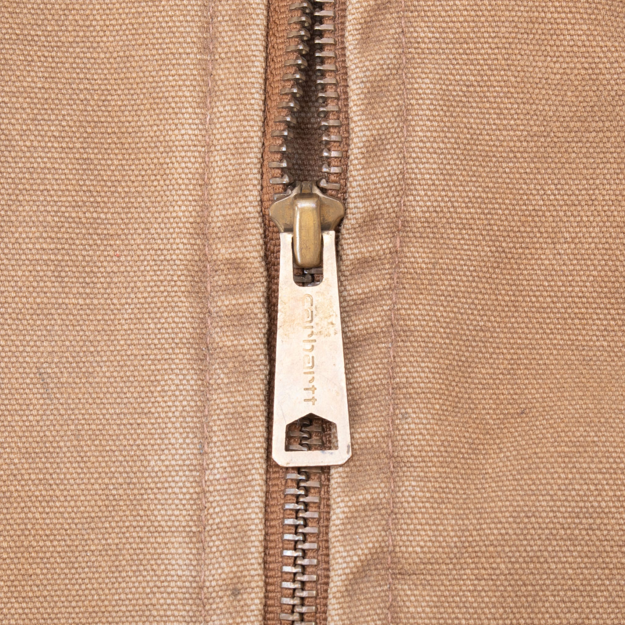 Close-up of Carhartt-branded metal zipper pull on brown vest