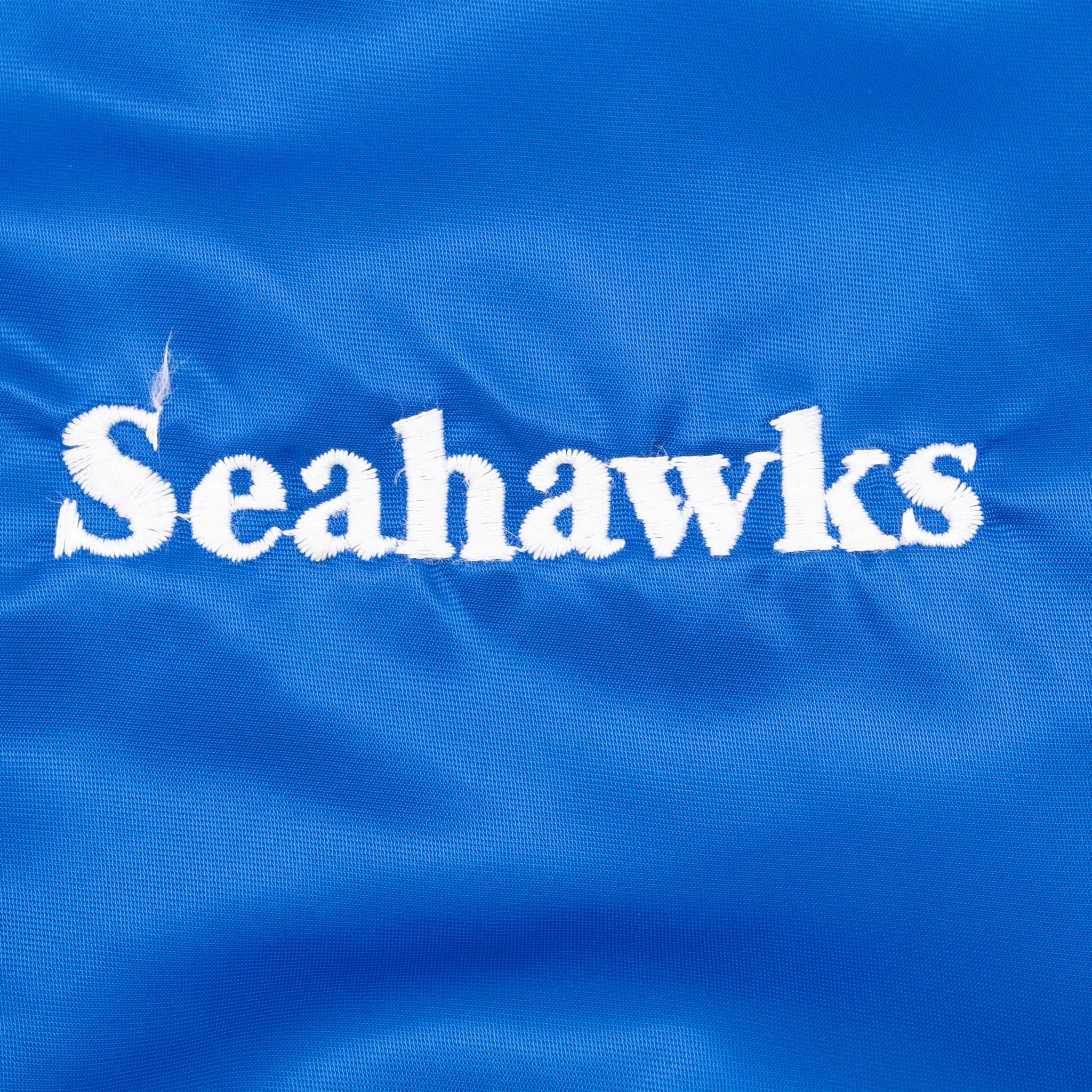 Close-up of white Seahawks chest embroidery on blue fabric