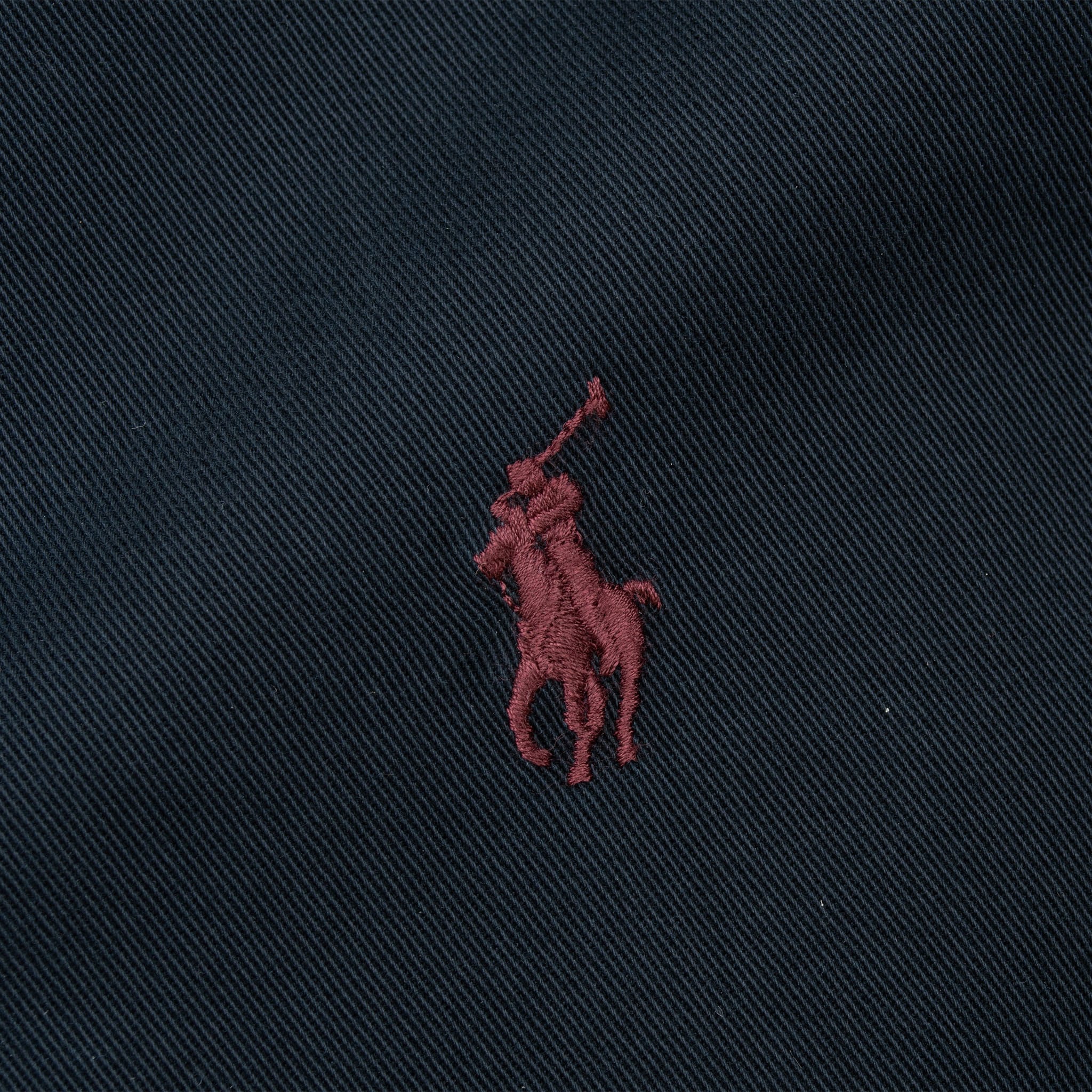 Close-up of burgundy Polo pony embroidery on navy fabric