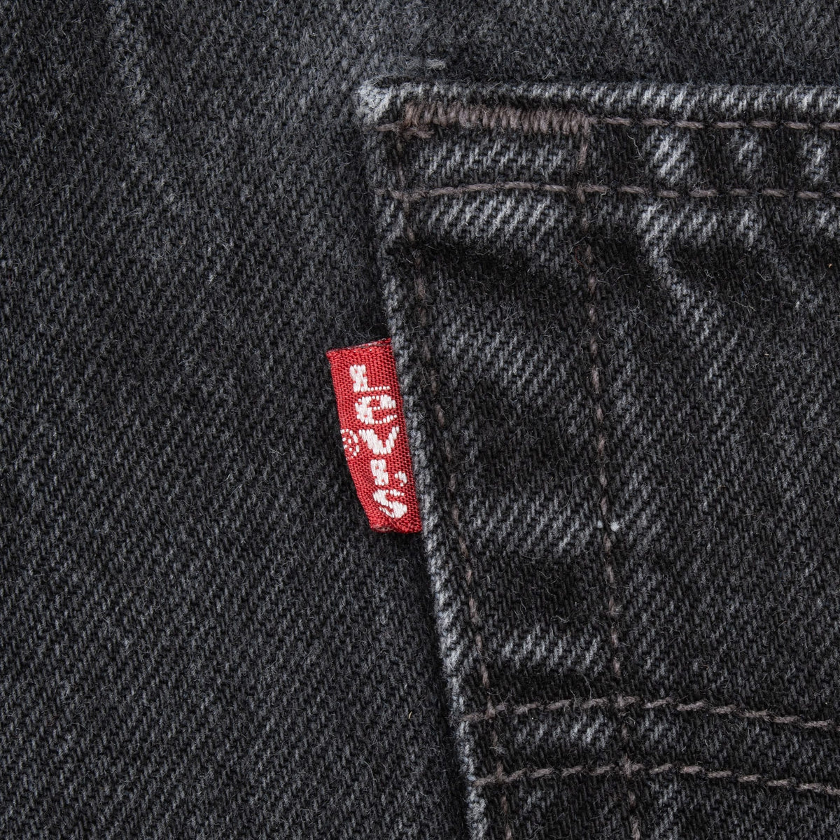 Close-up of Levi's red tab beside the rear pocket seam on black jeans