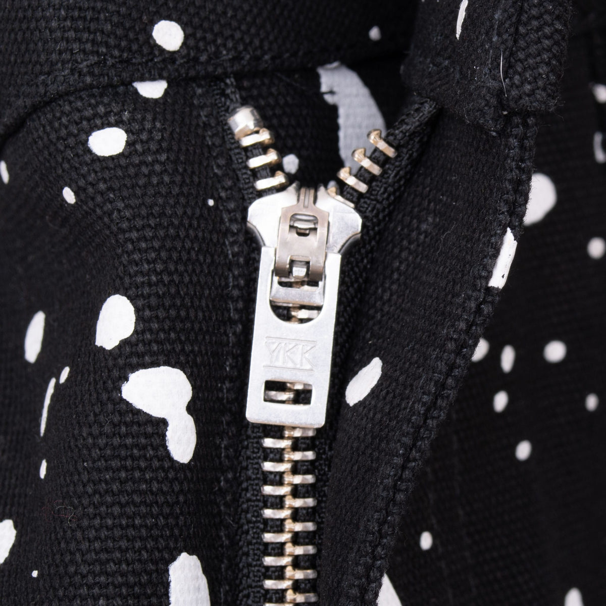 Close-up of metal YKK zip fly on black and white paint-splatter jeans