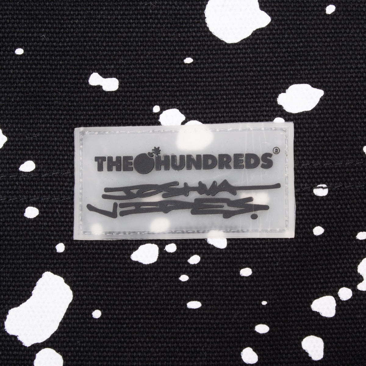 The Hundreds x Joshua Vides collaboration patch on black paint-splatter fabric