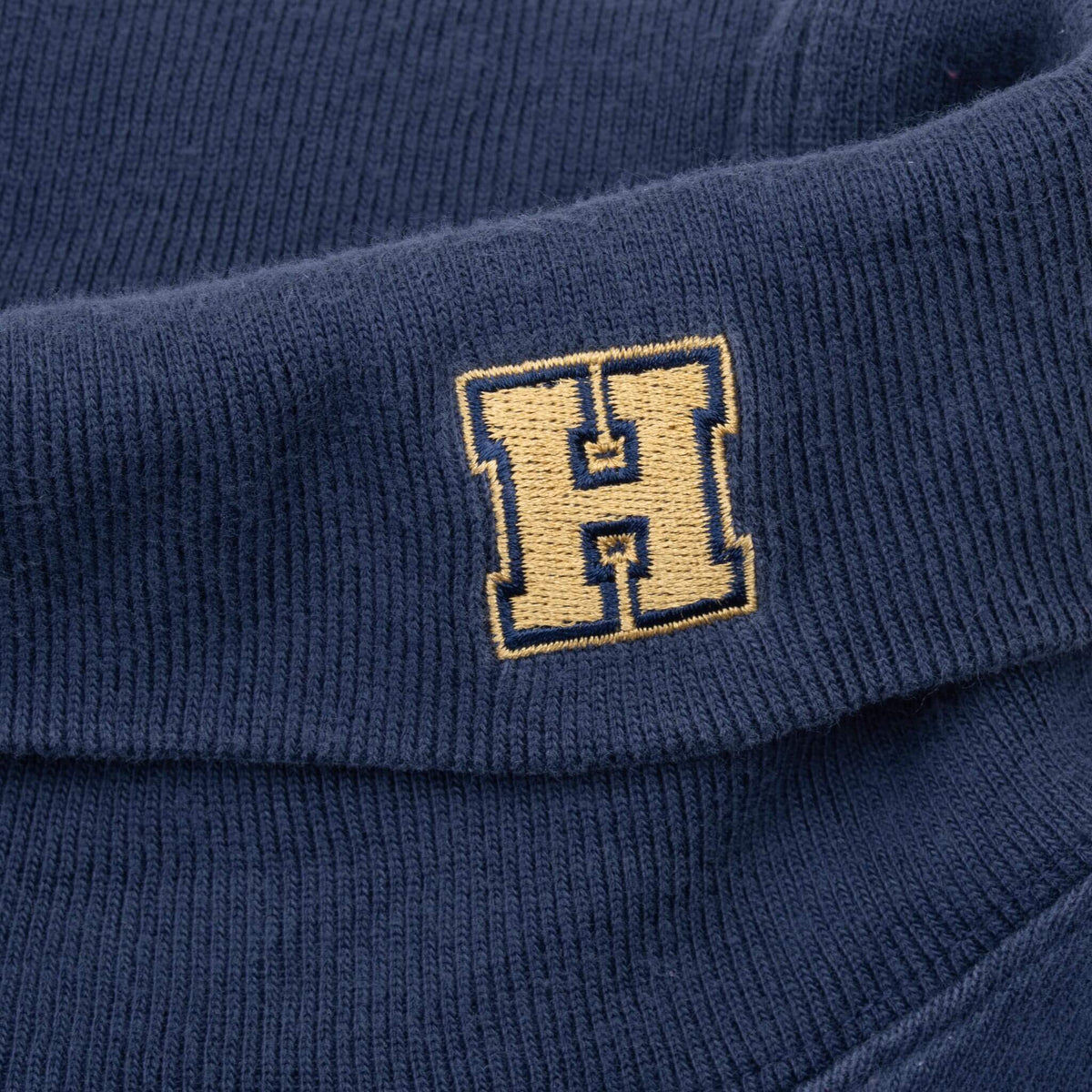 Gold outlined H embroidery on navy turtleneck collar