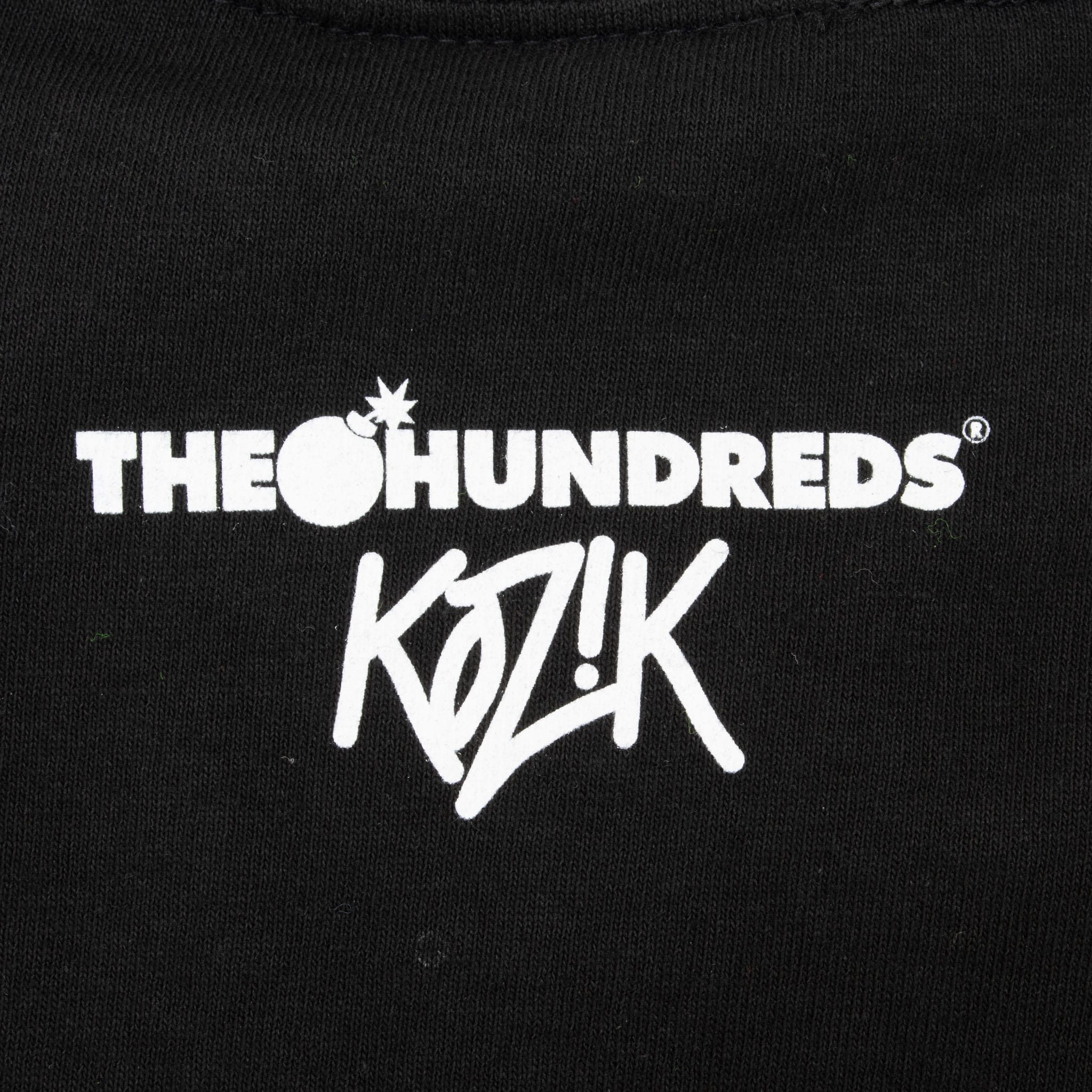 Close-up of white The Hundreds x Kozik logo printed below the back neckline