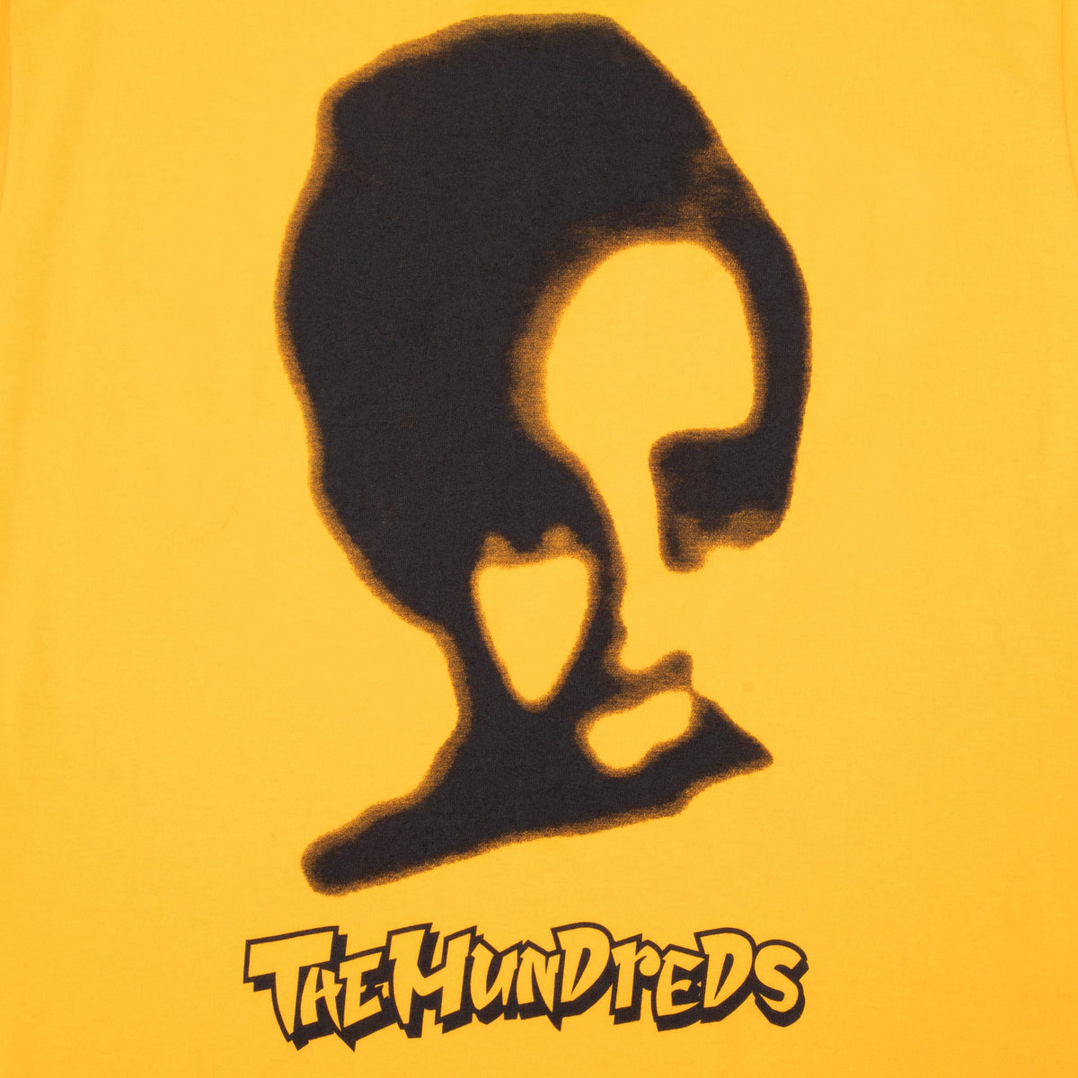 Close-up of black portrait and The Hundreds front print on mustard yellow Mallrats T-shirt