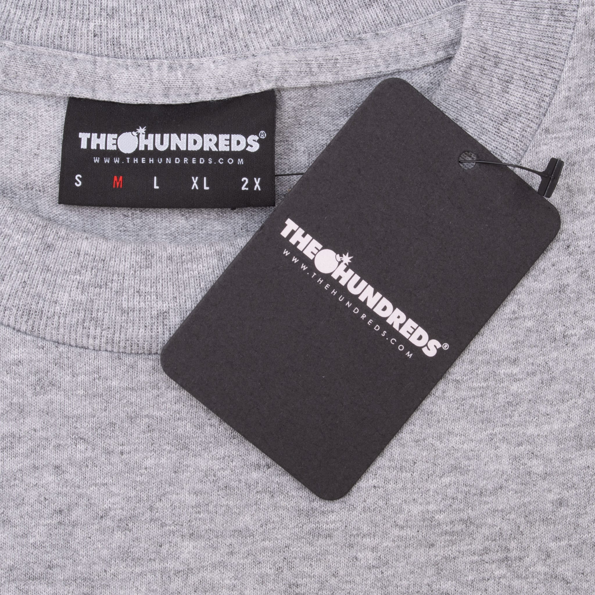 The Hundreds medium neck label and attached black hangtag on grey T-shirt