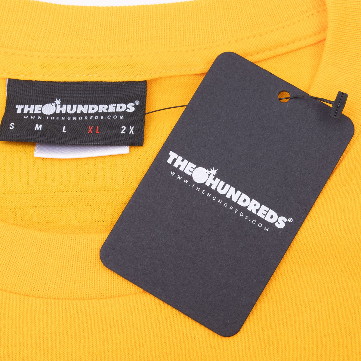 The Hundreds XL neck label and attached black hangtag on yellow T-shirt