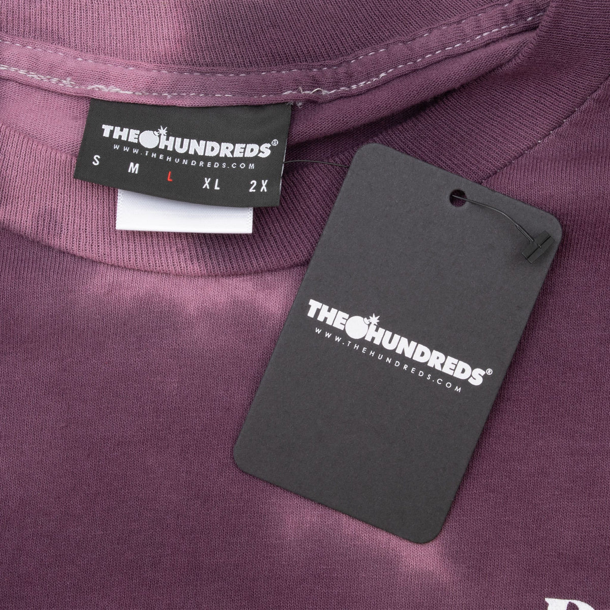 The Hundreds neck label with large size marked and attached black logo hangtag