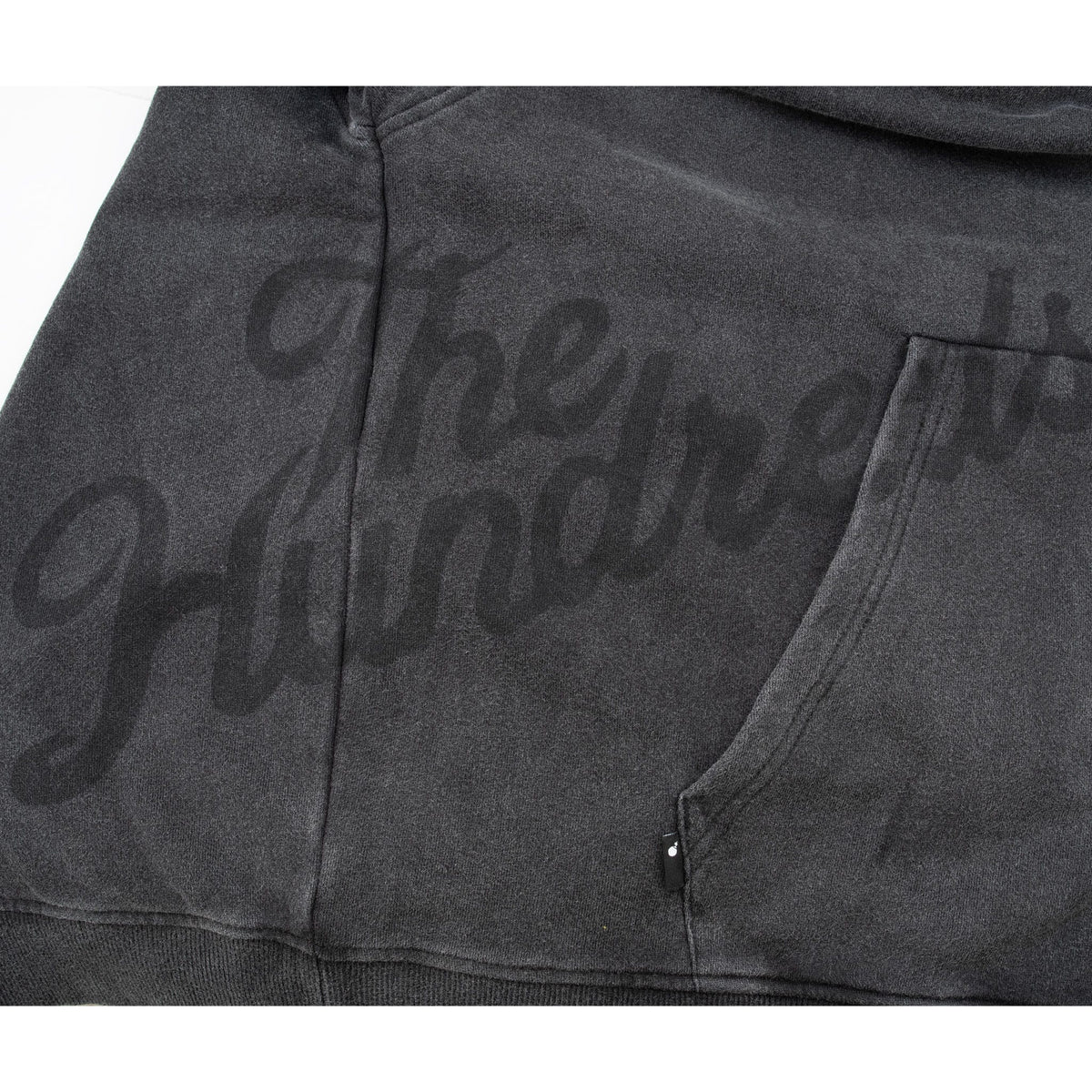 Close-up of tonal script graphic across the lower front and sleeve beside the kangaroo pocket