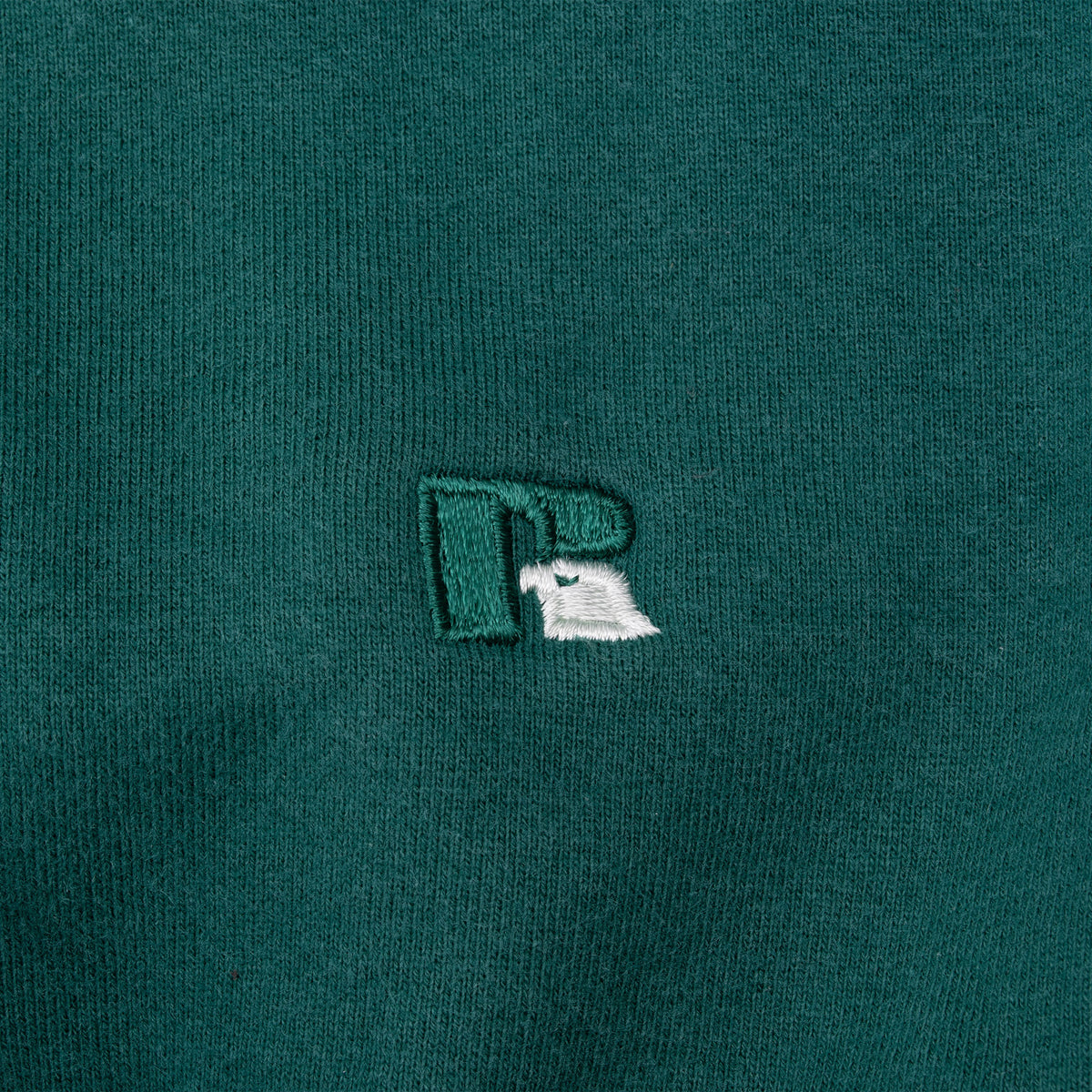 Close-up of embroidered Russell Athletic logo on green fabric