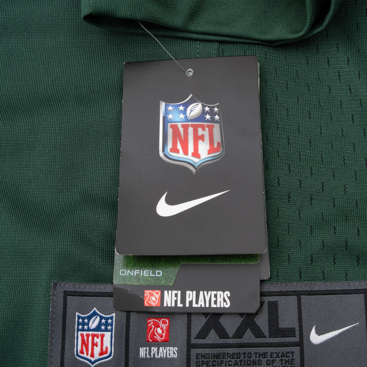 Attached NFL and Nike hangtags above the XXL hem label on green jersey fabric