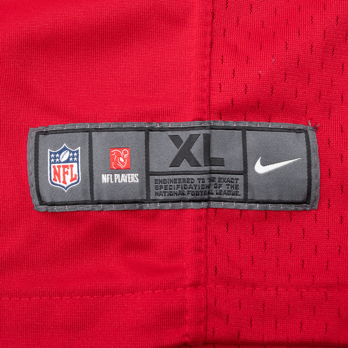Close-up of Nike NFL Players XL hem label on red jersey