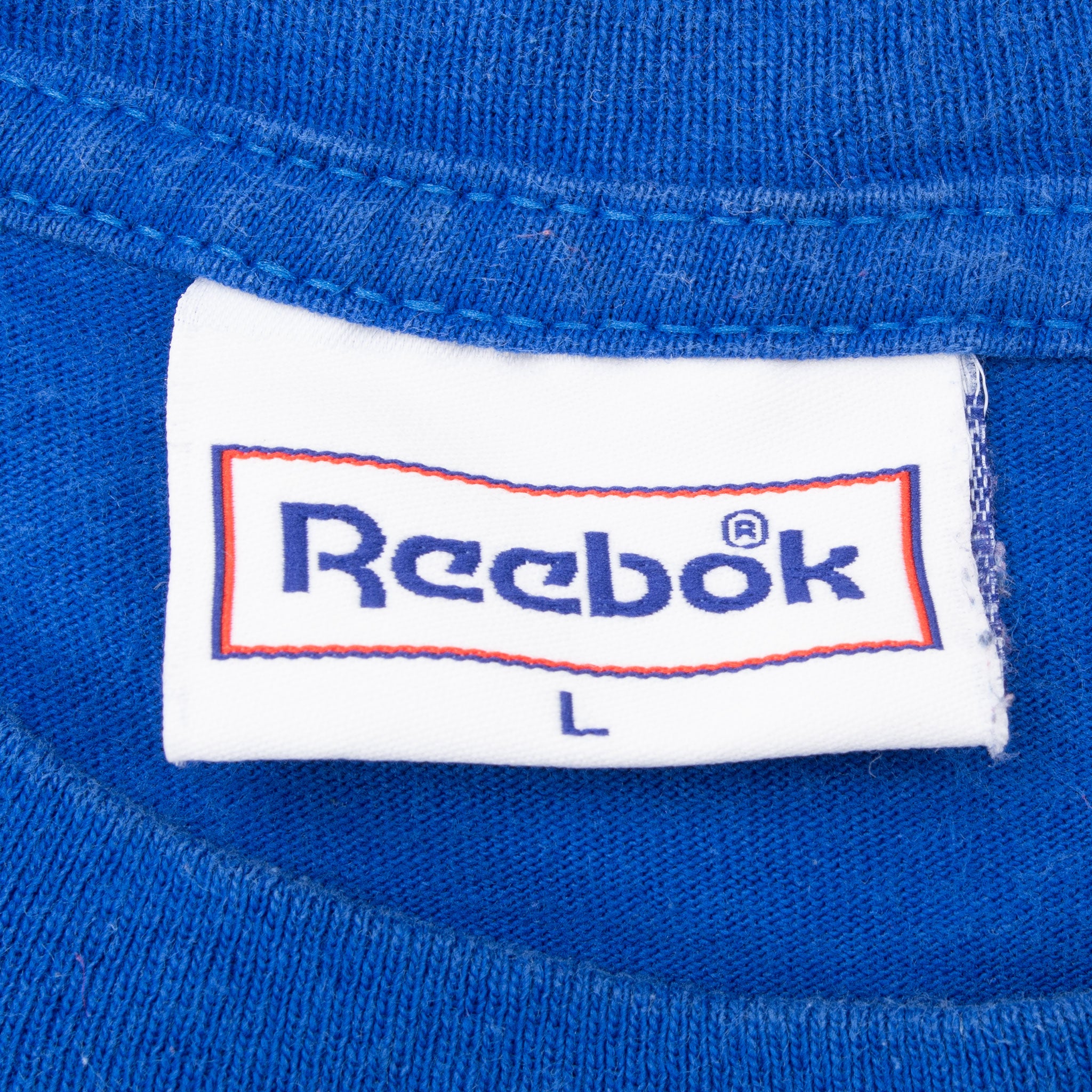 Close-up of Reebok size L neck tag on blue T-shirt