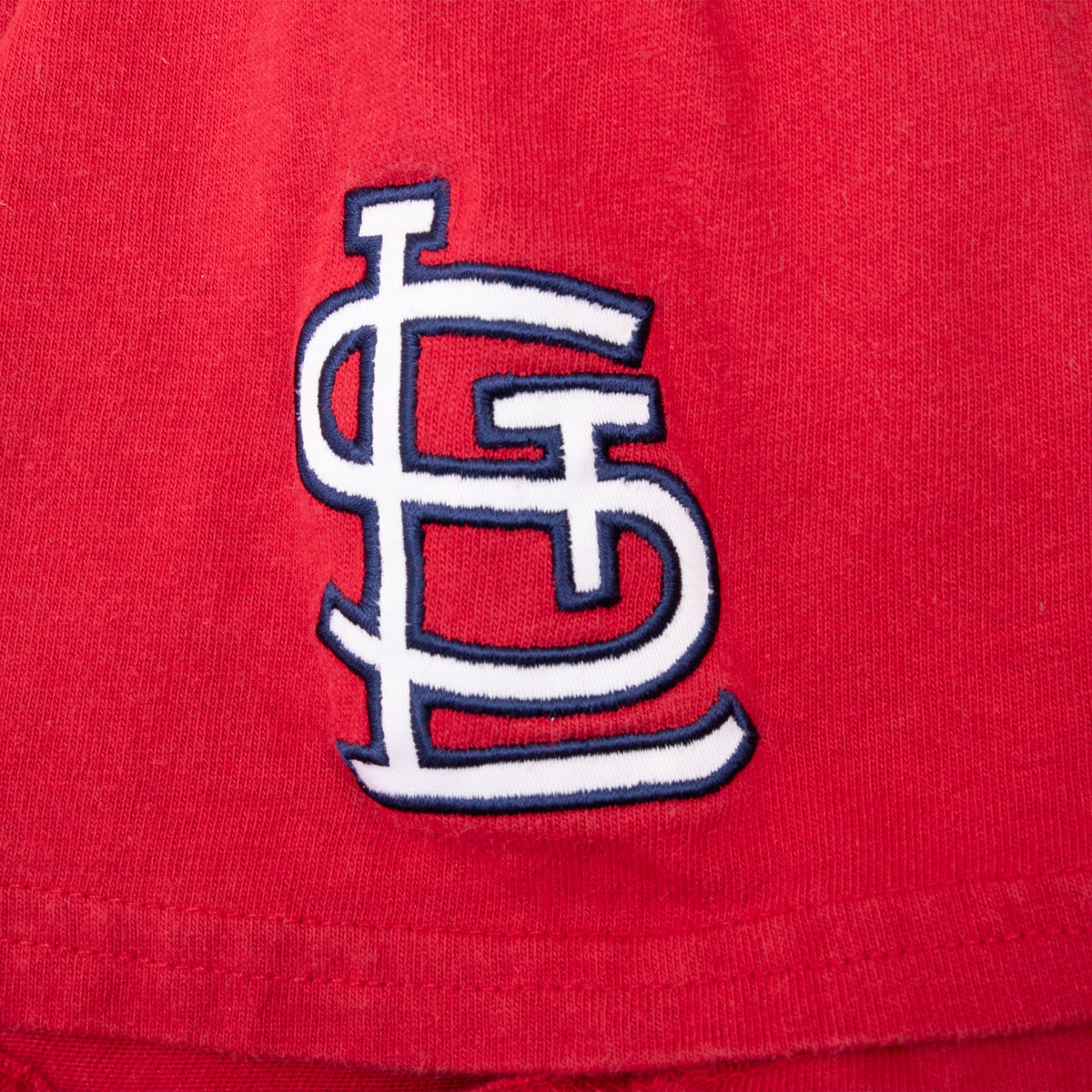 Close-up of interlocking StL embroidery on the red T-shirt sleeve