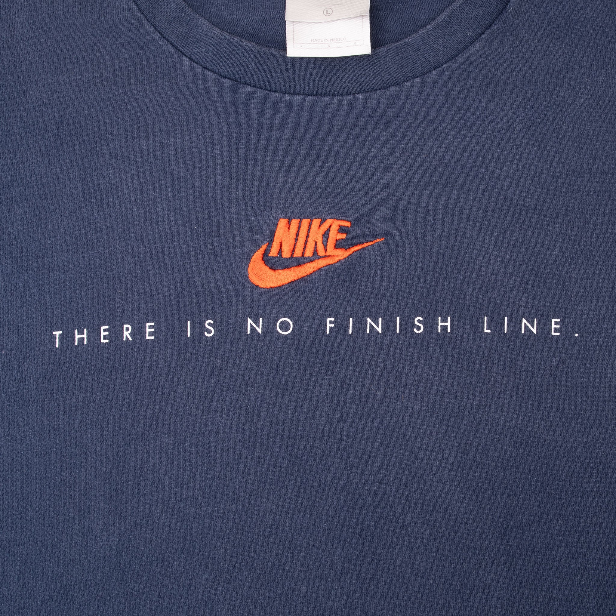 Close-up of orange Nike Swoosh and There Is No Finish Line chest graphic on blue T-shirt