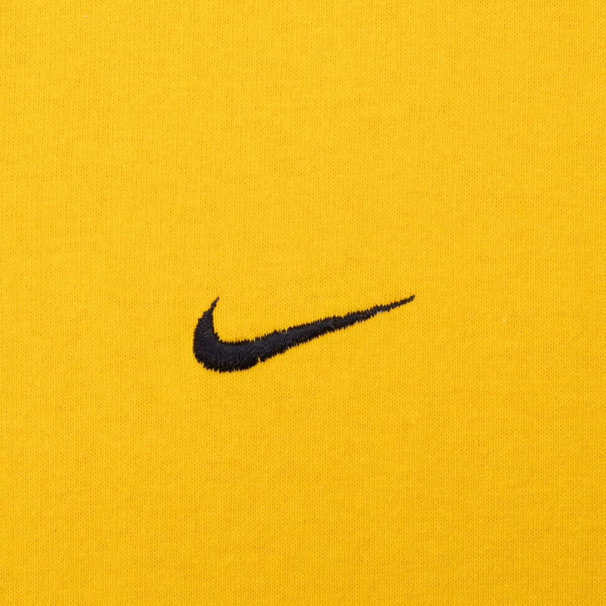 Close-up of black embroidered Nike Swoosh on yellow fabric