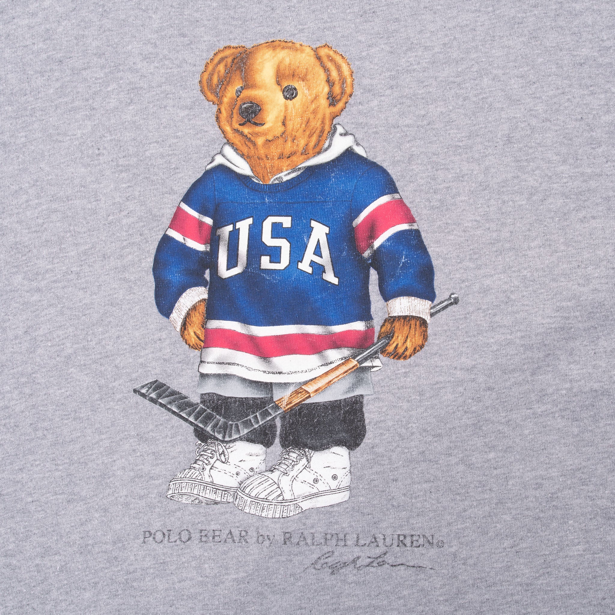 Close-up of Polo Bear graphic wearing a USA hockey jersey and holding a stick