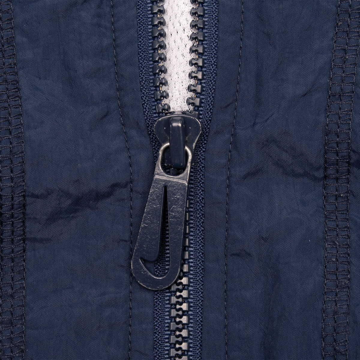 Close-up of blue front zipper pull with embossed Nike Swoosh
