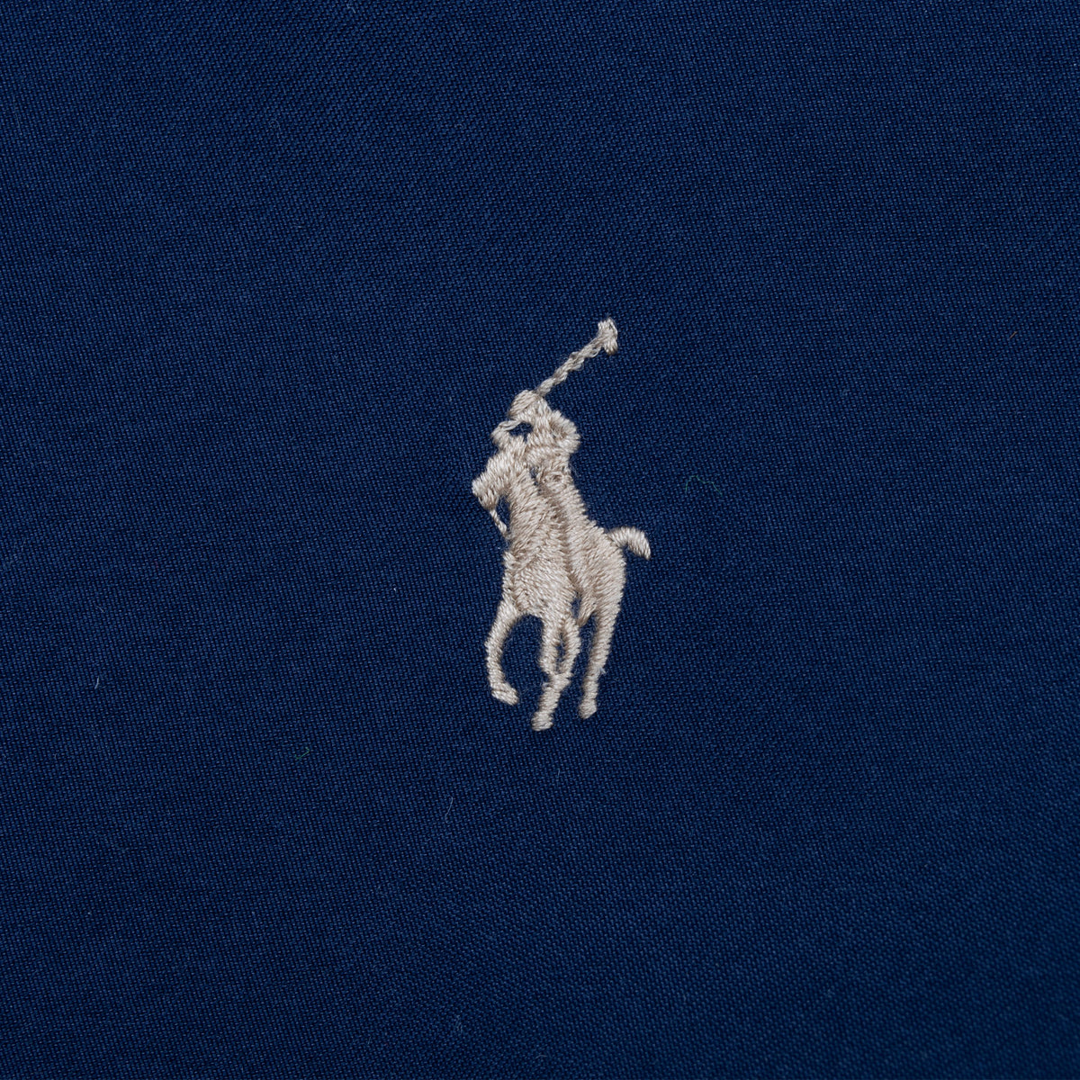 Close-up of embroidered Polo pony logo on navy blue jacket chest