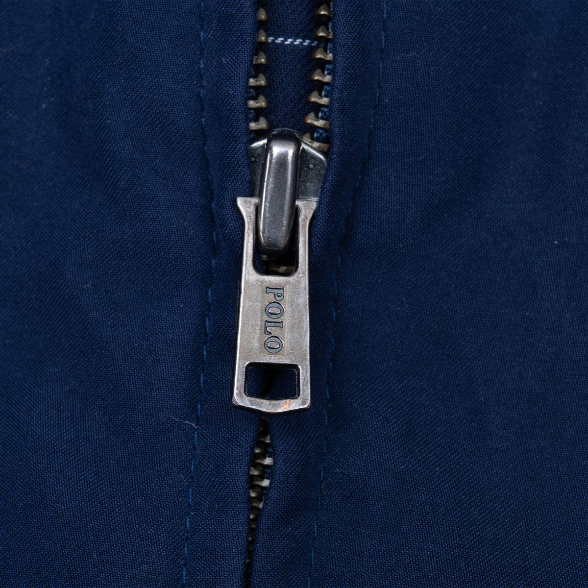 Close-up of metal Polo-branded zipper pull on navy blue jacket
