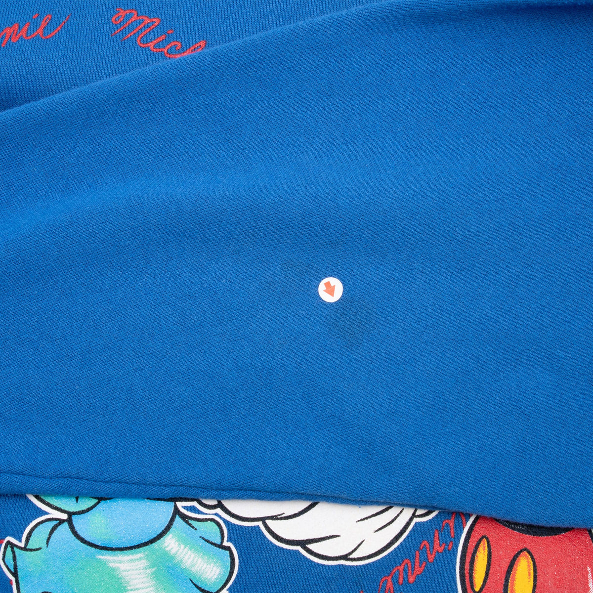 Close-up of blue sweatshirt front showing a small hole above the Mickey and Minnie graphic