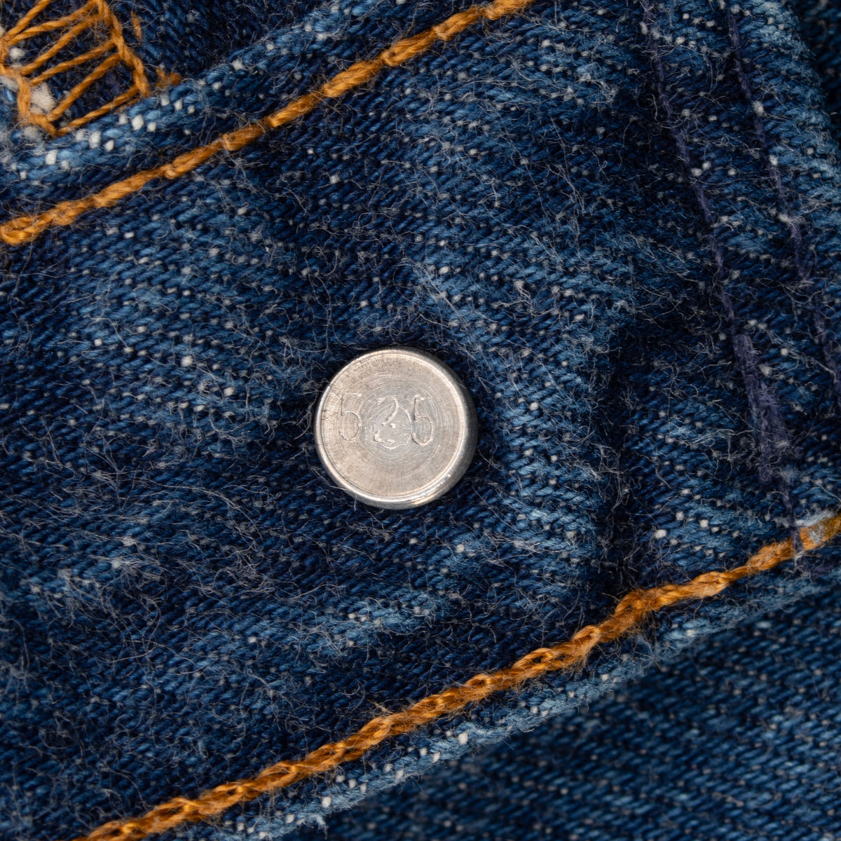 Close-up of Levi's 501 metal button stamped 525 on indigo denim