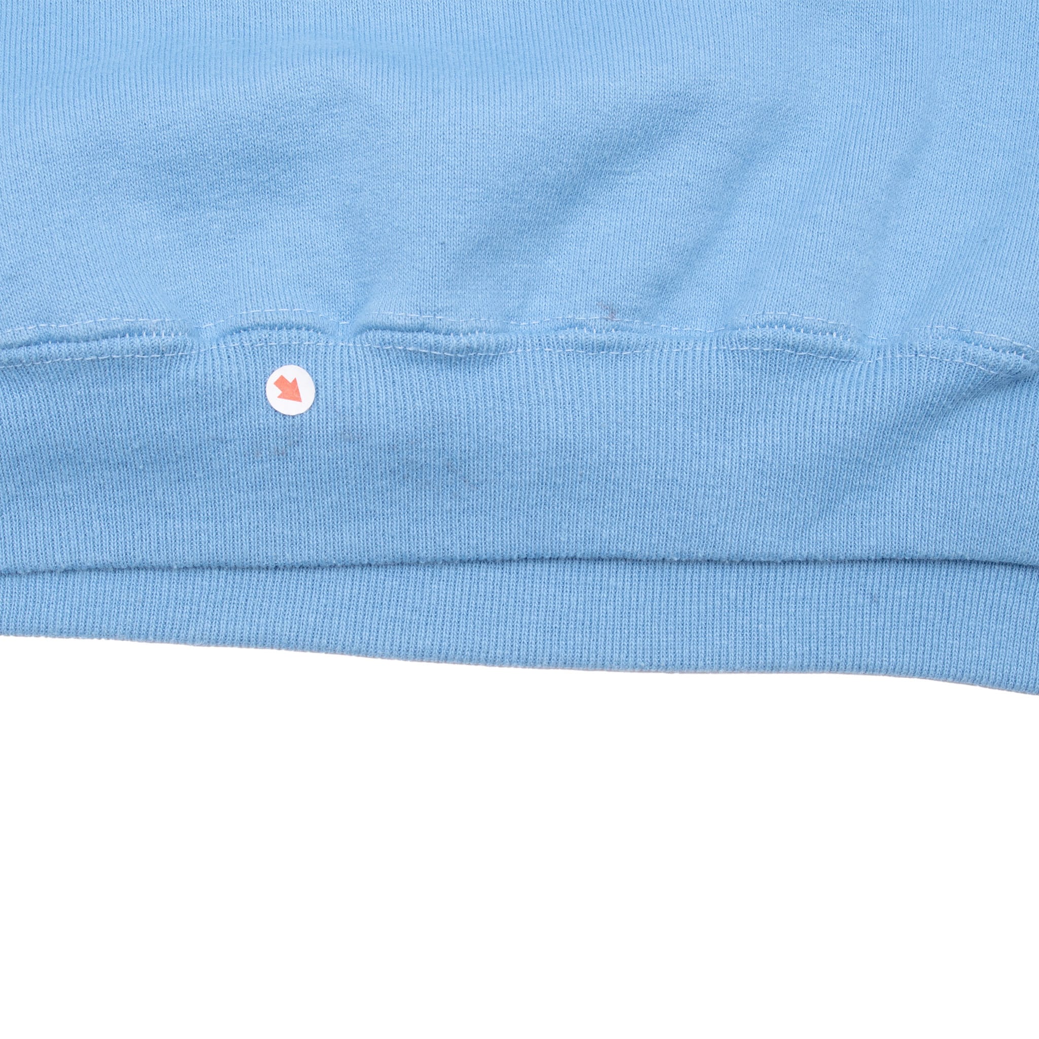 Close-up of blue ribbed sweatshirt hem with a small marked spot near the seam