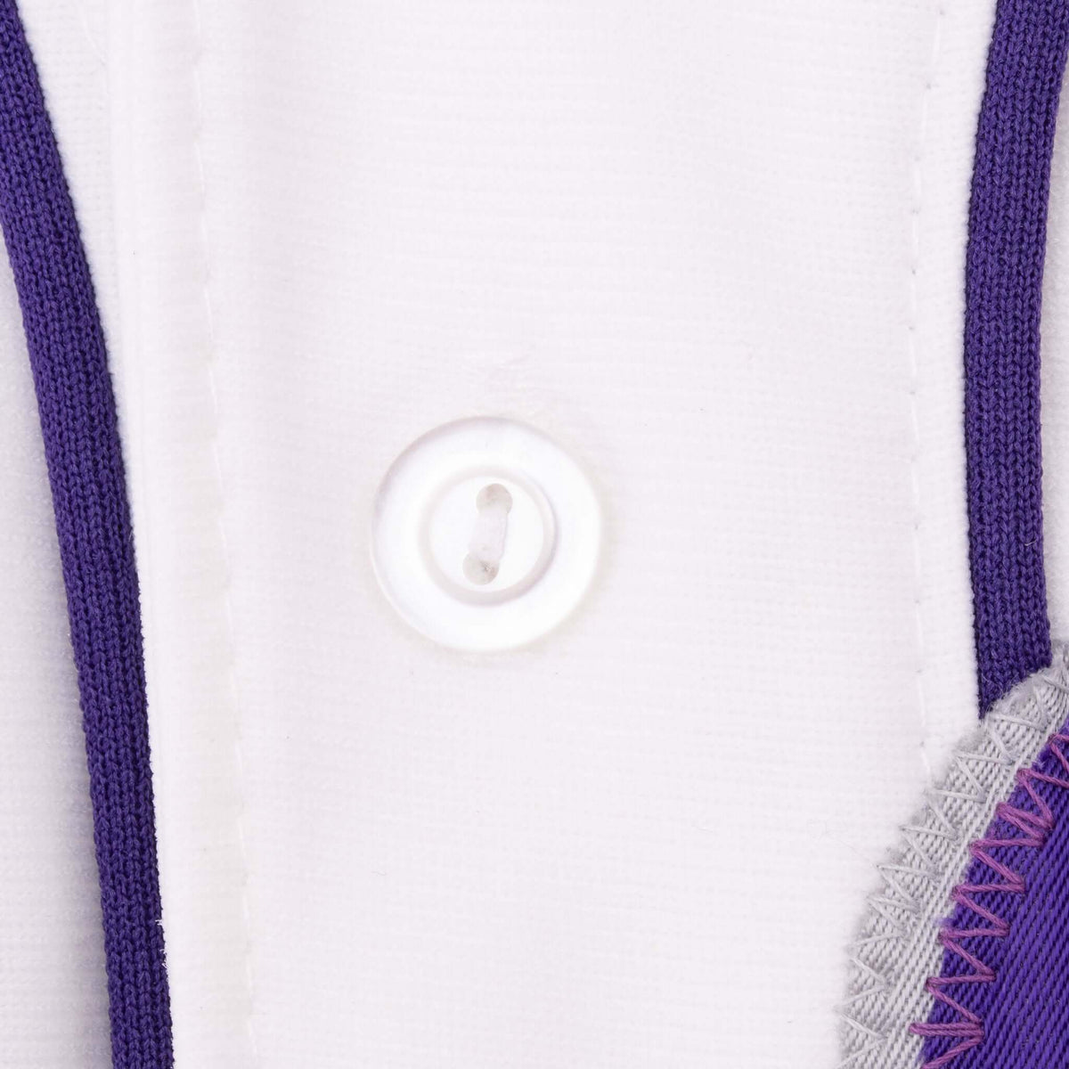 Close-up of white front button, purple piping, and number applique stitching