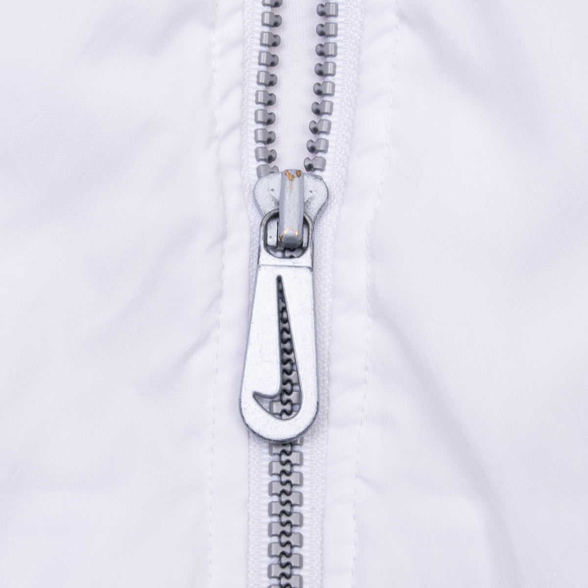 Close-up of gray front zipper and Nike Swoosh pull on white windbreaker