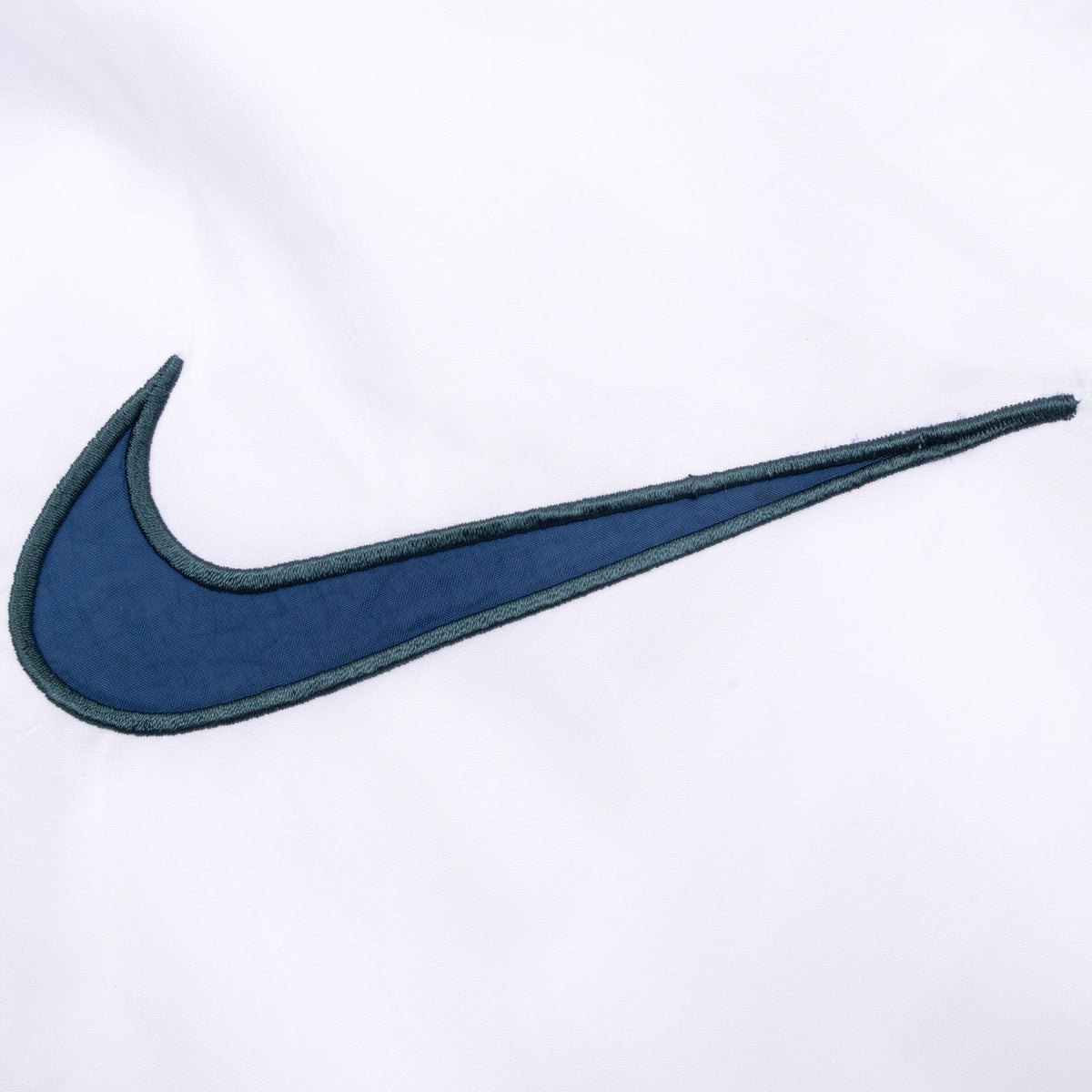 Close-up of large navy Nike Swoosh embroidery on white back panel