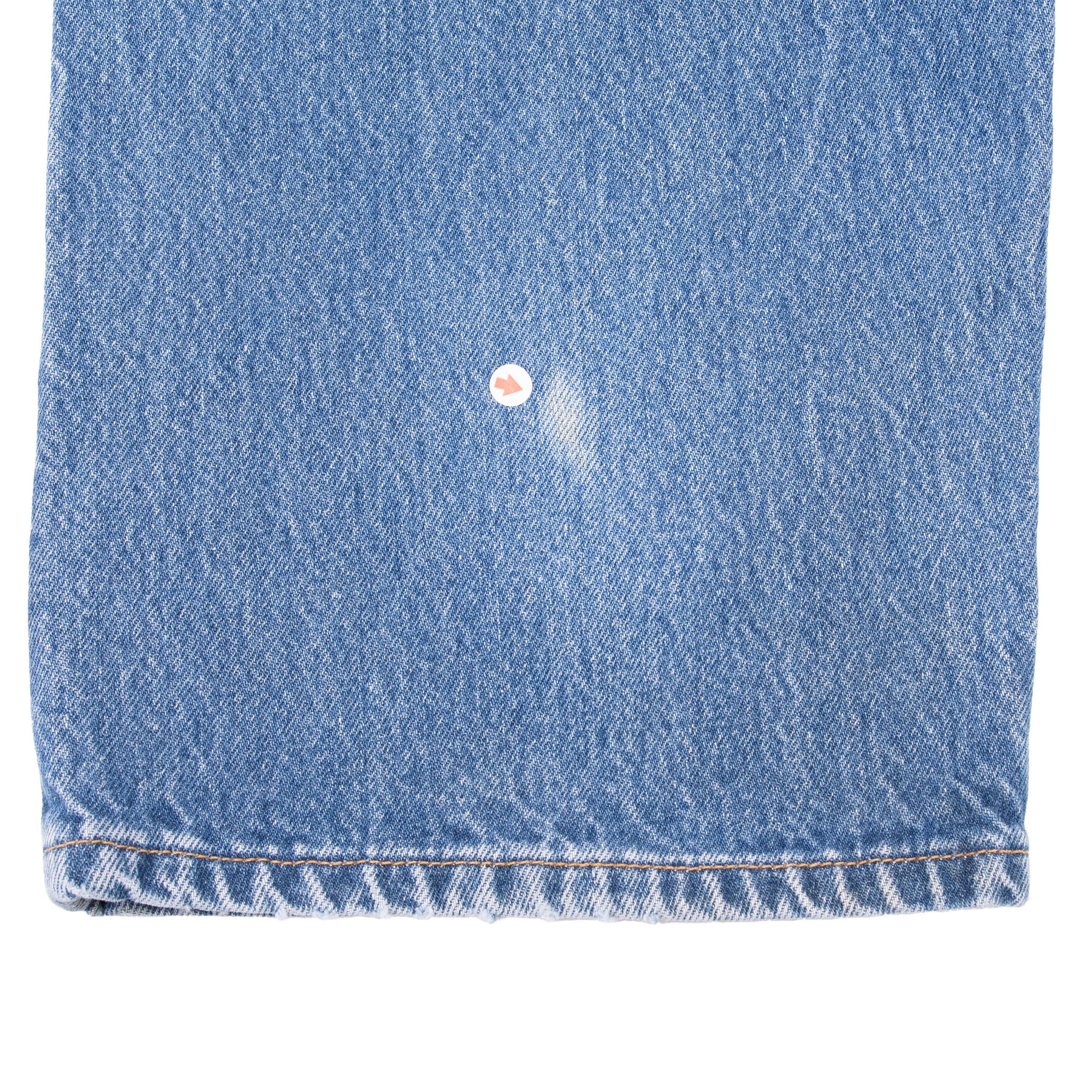 Close-up of jean leg near the hem with a small light worn spot