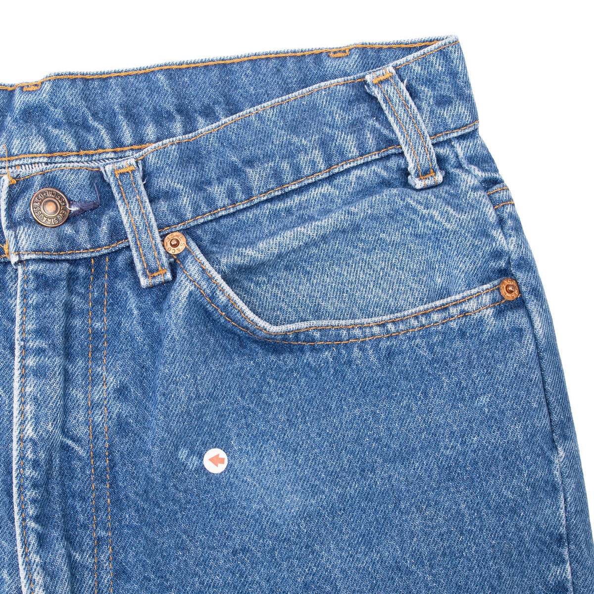 Close-up of the front pocket, belt loops and small arrow marker on the blue denim