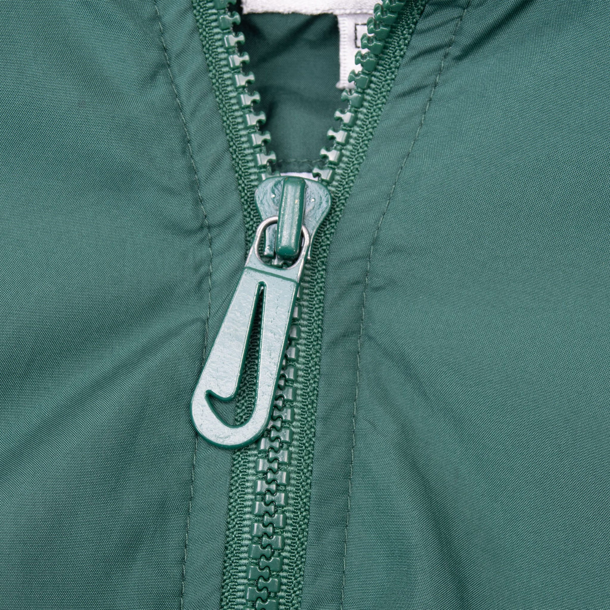 Close-up of green quarter-zip closure with Nike Swoosh zipper pull