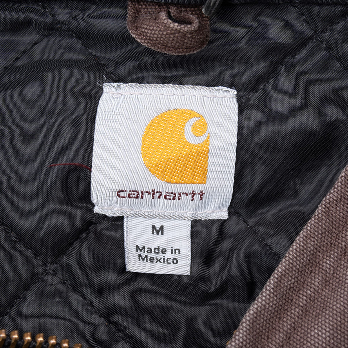 Carhartt neck label and medium size tag against black quilted lining