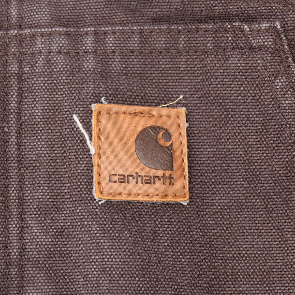 Close-up of Carhartt logo patch stitched to the dark brown front pocket