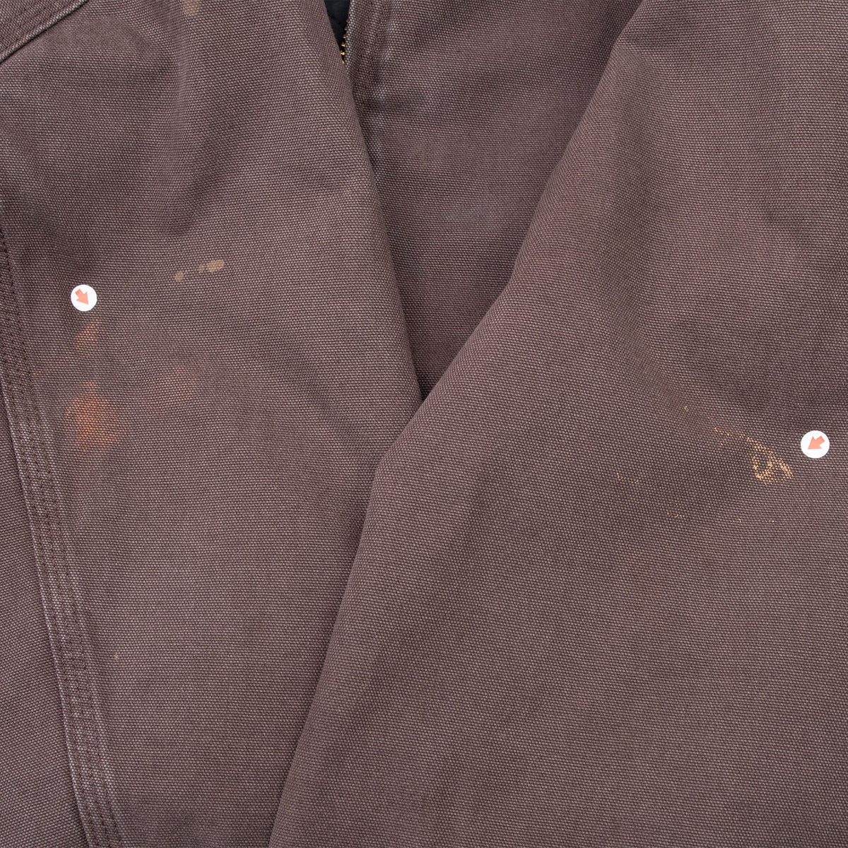 Close-up of small marks on the dark brown jacket sleeves, indicated by white markers