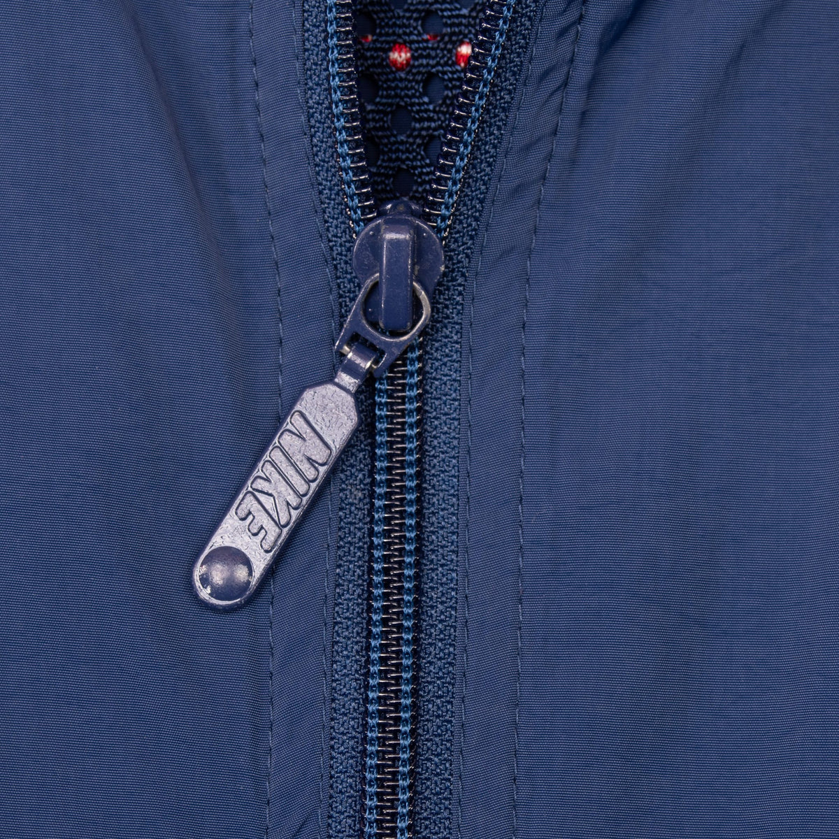 Close-up of Nike-branded zipper pull on navy windbreaker