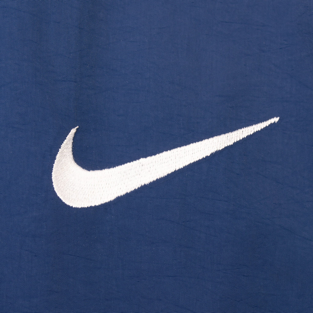 Close-up of white embroidered Nike Swoosh on navy fabric