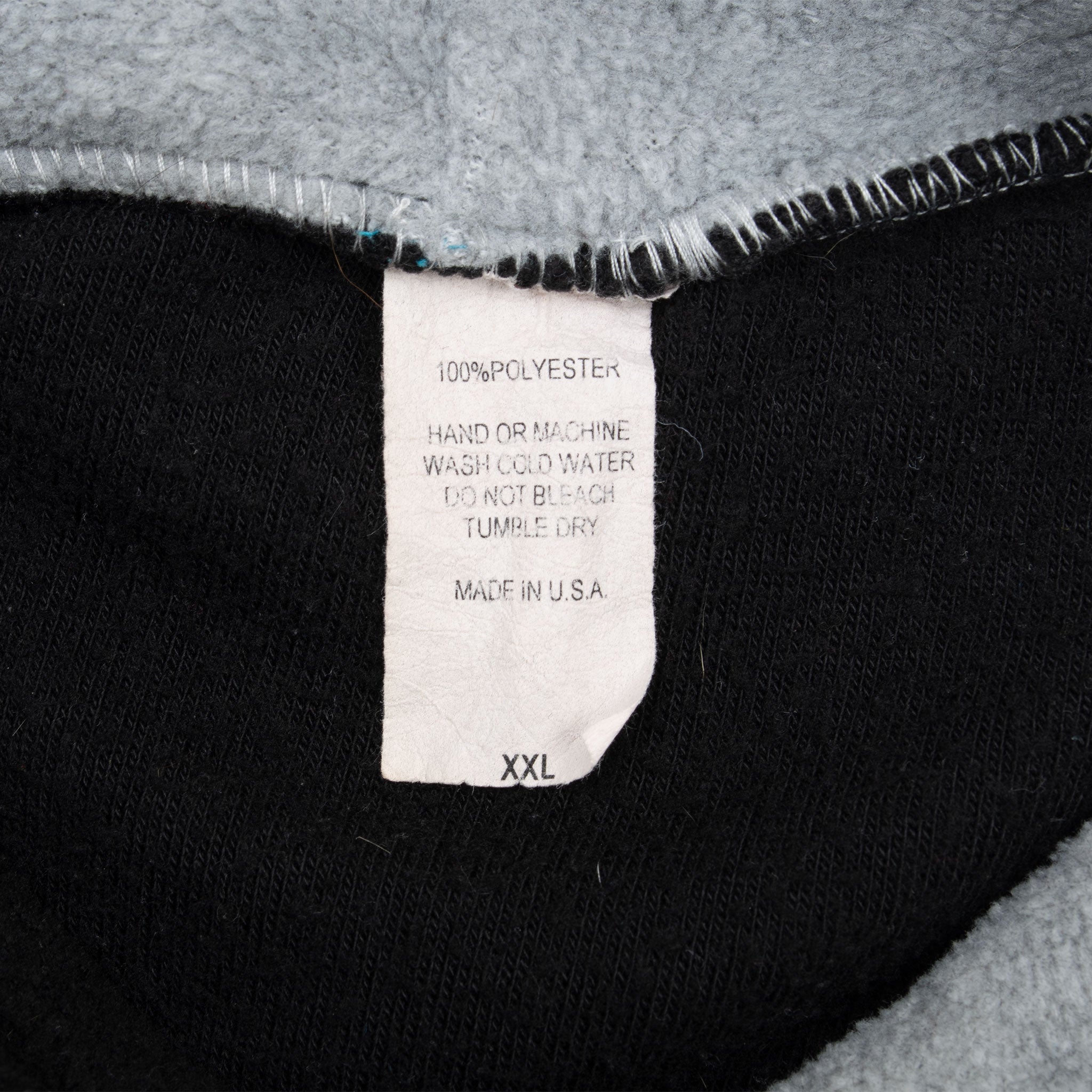Close-up of hoodie care tag marked 100% polyester, made in USA, and XXL