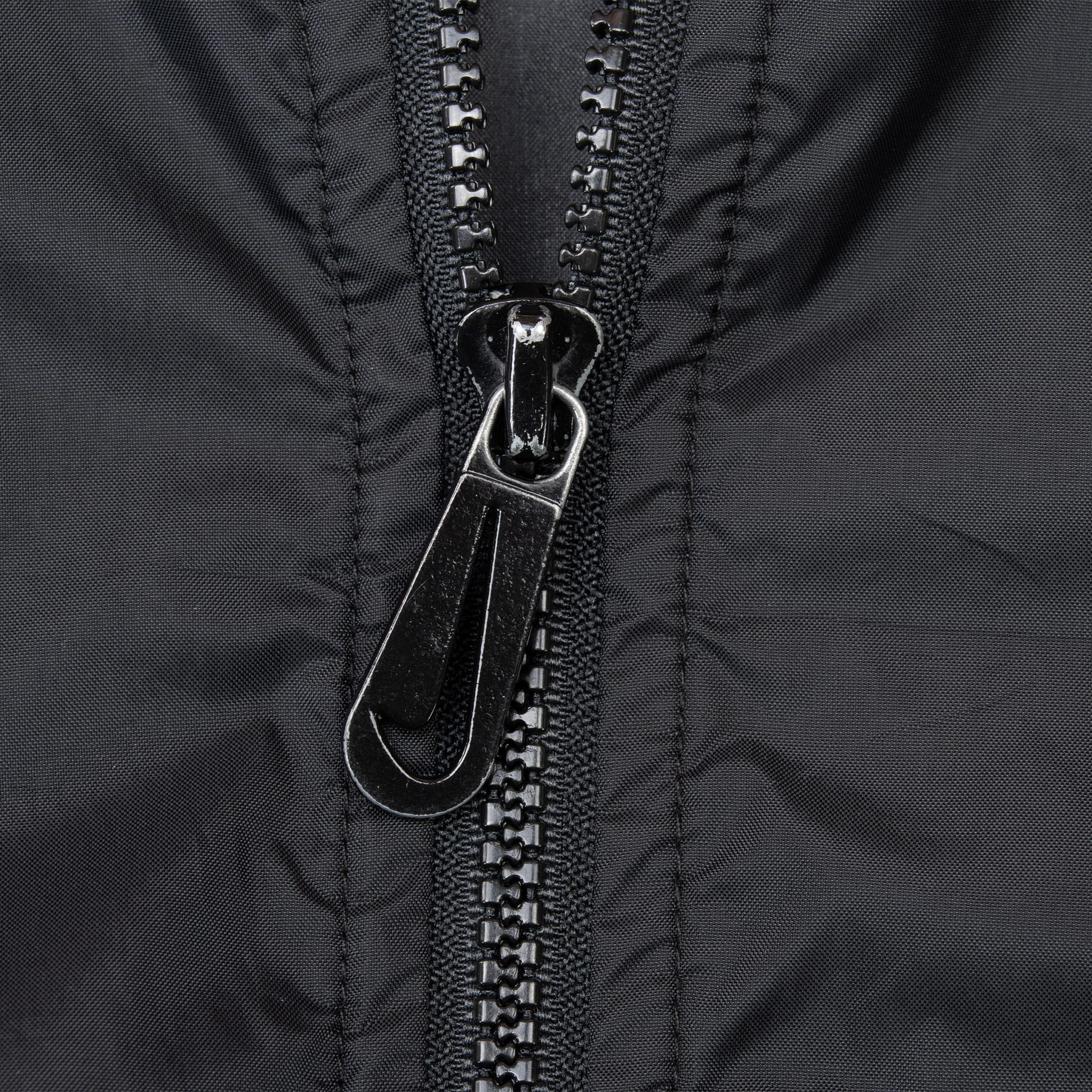 Close-up of black front zipper and Nike Swoosh-shaped zipper pull