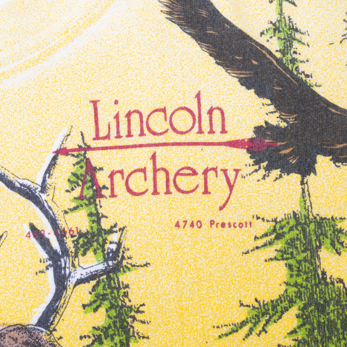 Close-up of red Lincoln Archery branding beside an eagle and evergreen trees