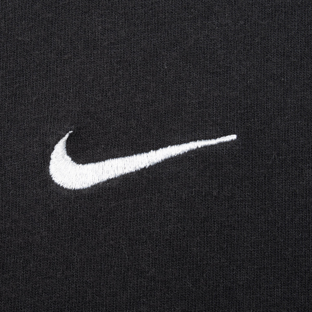 Close-up of white embroidered Nike Swoosh on black fabric