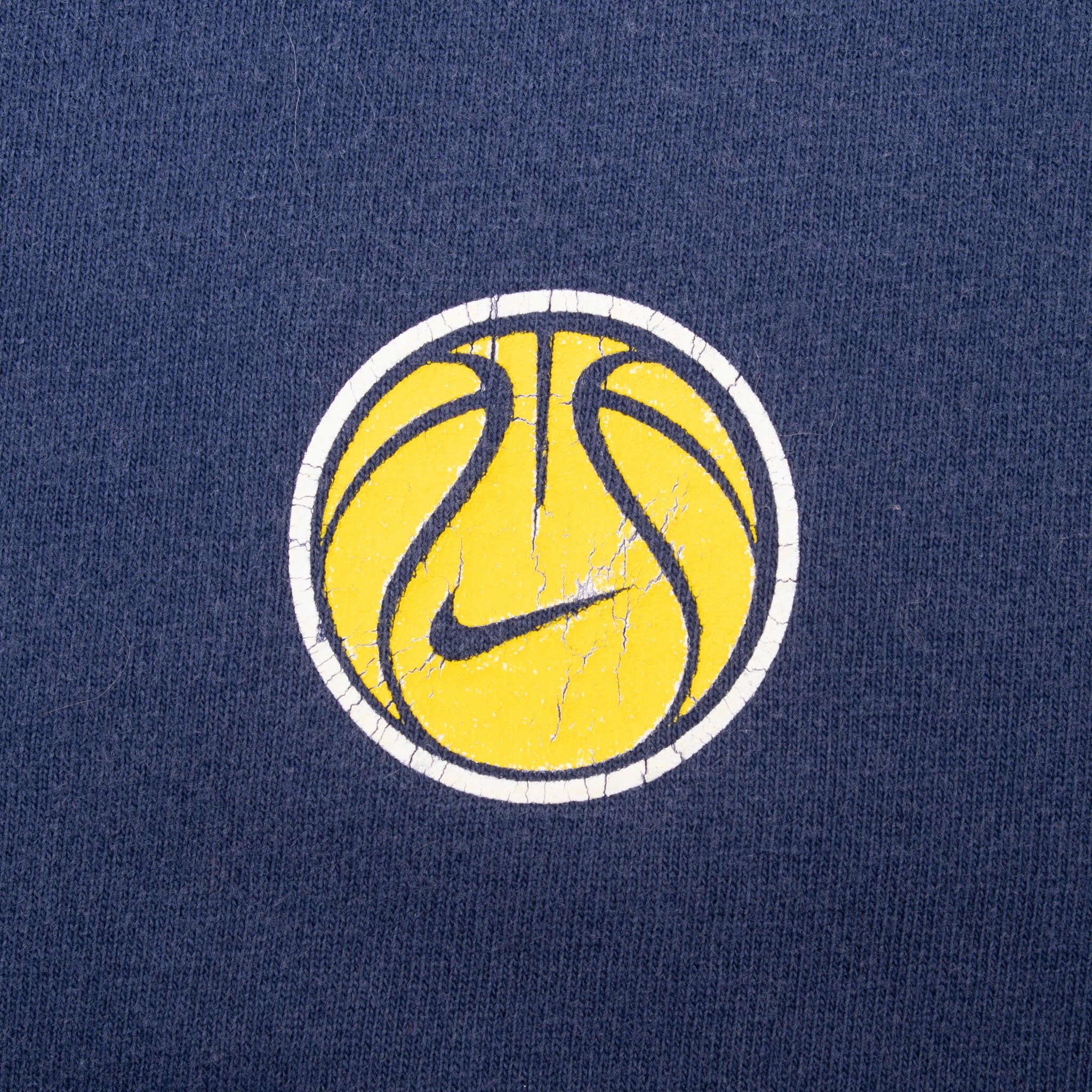 Close-up of yellow basketball and Nike Swoosh chest graphic on navy fabric